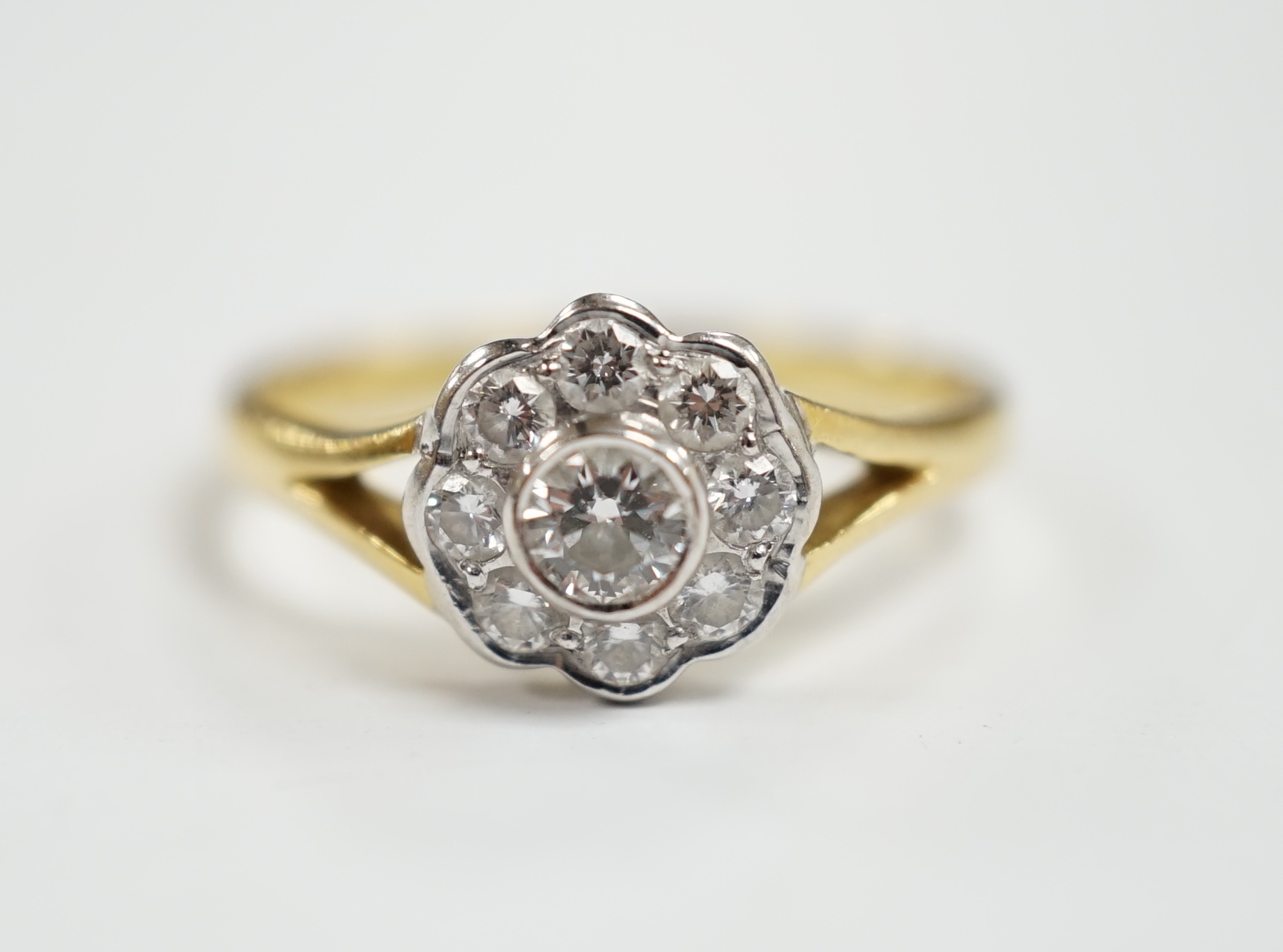 A modern 18ct gold and nine stone diamond set flower head cluster ring, size M, gross weight 3 grams.